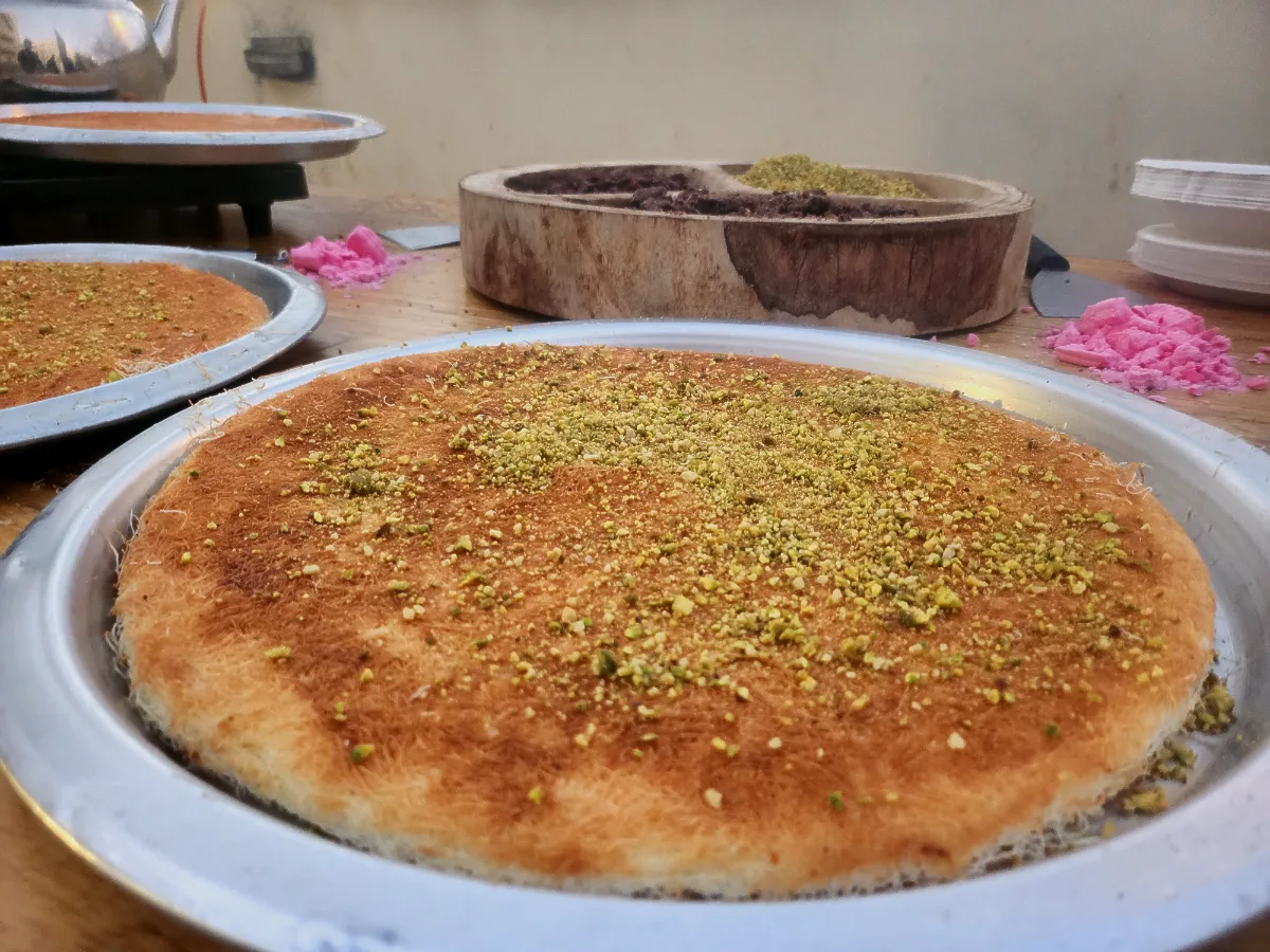 שף מבית טרפת אירועים מכין מנת חמה ונמתחת על מגש נחושת מסורתי